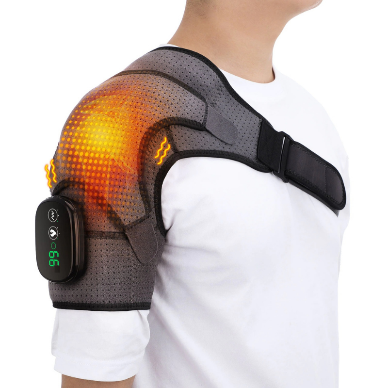 A person wearing a black heated shoulder brace wrap with a visible LED control display on the upper arm.