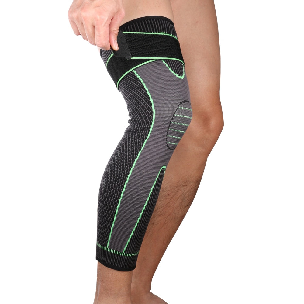 A person wearing a black compression leg sleeve with green accents and straps around the knee area.