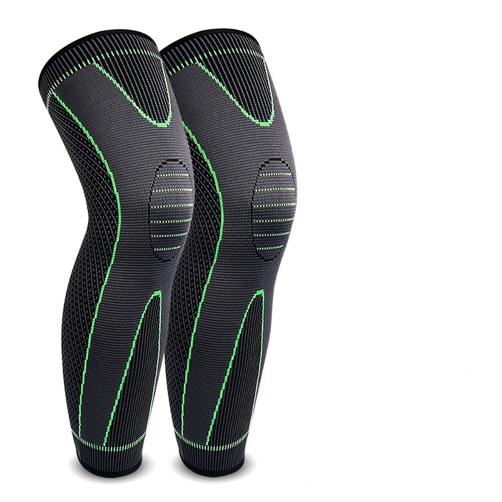 A pair of black compression leg sleeves with green accents designed for athletic activities, featuring an elastic band around the calf area.